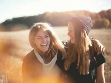 Zwei Frauen lachen auf einem Feld im Herbst | © Getty Images/Johner Images