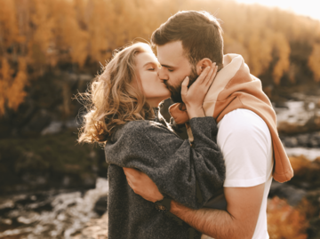 Mann und Frau küssen sich vor herbstlichem Wald | © Getty Images/Elizaveta Starkova