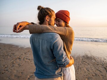 Mann und Frau umarmen sich verliebt am Strand | © Getty Images/Westend61