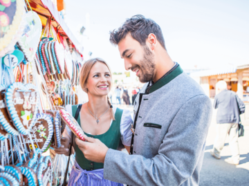 Mann und Frau vor Lebkuchenherzenstand auf dem Oktoberfest | © Getty Images/Patrick Frost