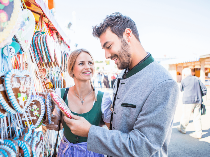 Mann und Frau vor Lebkuchenherzenstand auf dem Oktoberfest | © Getty Images/Patrick Frost