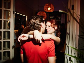 Frau umarmt Mann auf Party | © Getty Images/Thomas Barwick