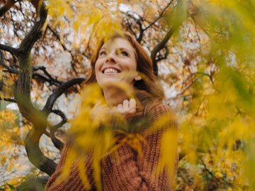 Frau unter Herbstblättern | © Getty Images/Westend61