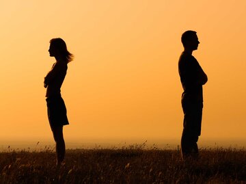 Frau und Mann auf einem Feld stehen Rücken an Rücken | © Getty Images/LittleBee80