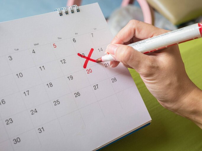 Frau streicht Datum in Kalender an. | © Getty Images/Chakrapong Worathat