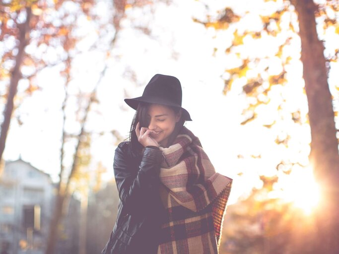 Frau mit Hut vor Herbstbäumen | © Getty Images/freemixer