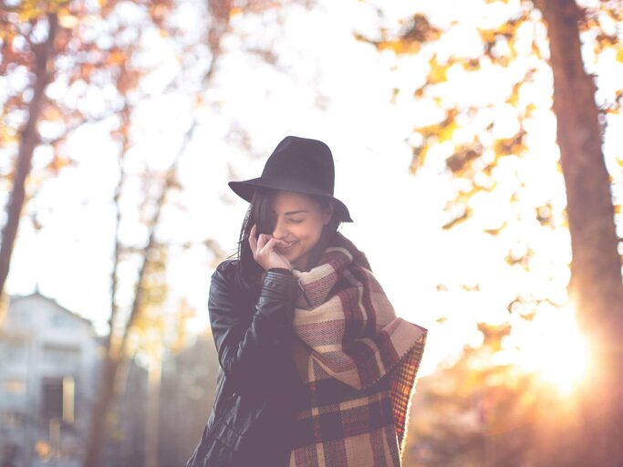 Frau mit Hut vor Herbstbäumen | © Getty Images/freemixer