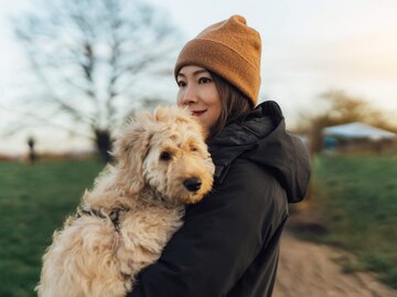 Frau sieht glücklich aus und hält Hund auf dem Arm | © Getty Images/Oscar Wong