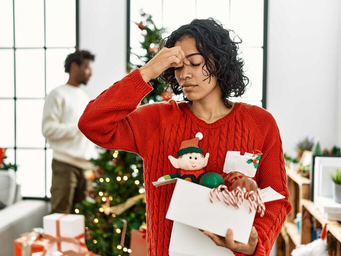 Gestresste Frau vor einem Weihnachtsbaum | © Getty Images/AaronAmat