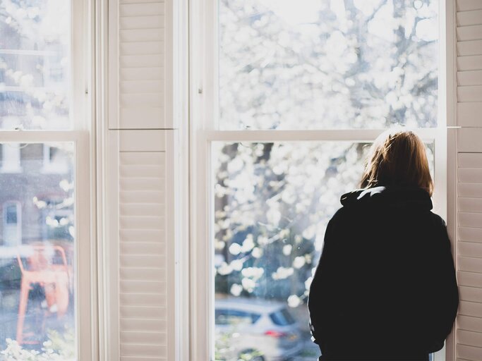 Frau steht am Fenster und schaut raus | © Getty Images/Photographer, Basak Gurbuz Derman