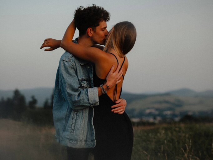 Mann und Frau umarmen sich auf Wiese | © Getty Images/Halfpoint Images