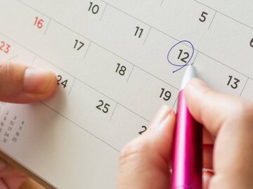 Hand streicht Datum in Kalender an | © Getty Images/Kwangmoozaa
