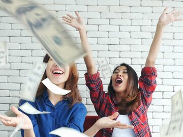 Glückliche Frauen werfen Geld in die Luft | © Getty Images/howtogoto