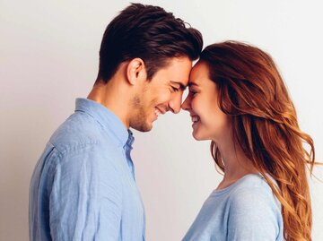 Glückliches junges Paar steht sich lachend gegenüber | © Getty Images/Westend61