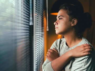 Frau schaut aus dem Fenster ist traurig | © Getty Images