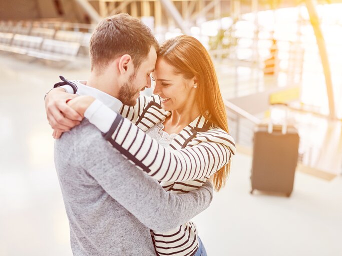 Frau und Mann umarmen sich am Flughafen | © AdobeStock/Robert Kneschke