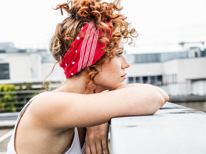 Junge Frau mit Haarband blickt in die Ferne | © Getty Images/Westend61