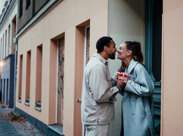 Liebespaar steht auf der Straße und küsst sich verliebt.  | © Getty Images / Alina Rudya/Bell Collective