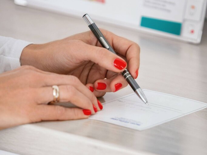 Frau mit lackierten Fingernägeln schreibt auf Papier | © Getty Images/Aja Koska
