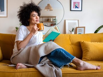 Person sitzt mit Kaffeetasse auf Couch | © Getty Images/Daniel de la Hoz