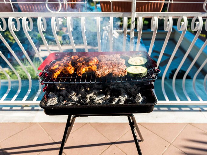 Grill mit leckerem Gemüse und Fleisch auf einem Balkon | © Getty Images/_jure