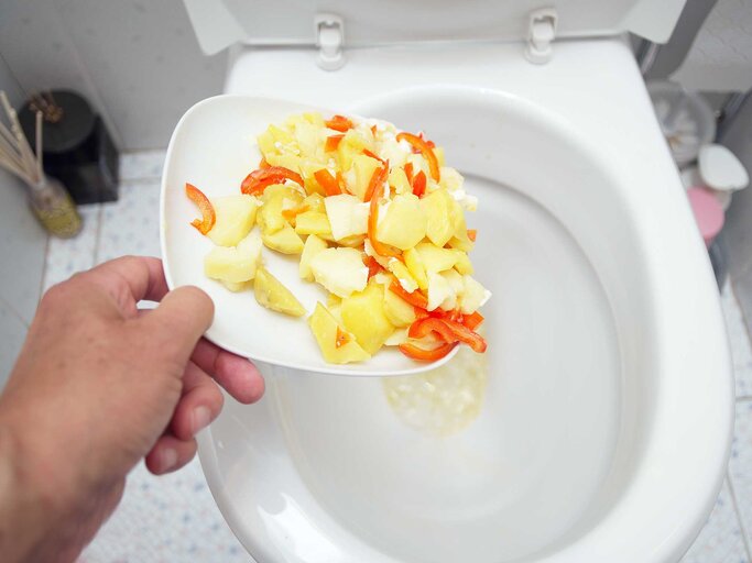 Person schmeißt Essensreste ins Klo. | © Getty Images / victorass88