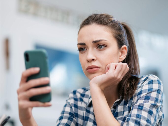 Frau sieht schockiert auf ihr Handy | © gettyimages.de | Ivan Pantic