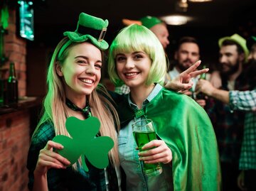 Zwei junge Frauen feiern St. Patrick's Day in grünen Klamotten in einem Pub. | © gettyimages.de | vadimguzhva