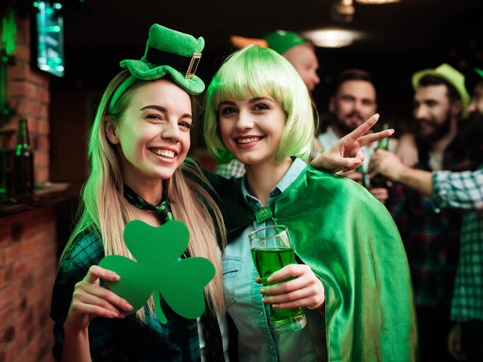Zwei junge Frauen feiern St. Patrick's Day in grünen Klamotten in einem Pub. | © gettyimages.de | vadimguzhva
