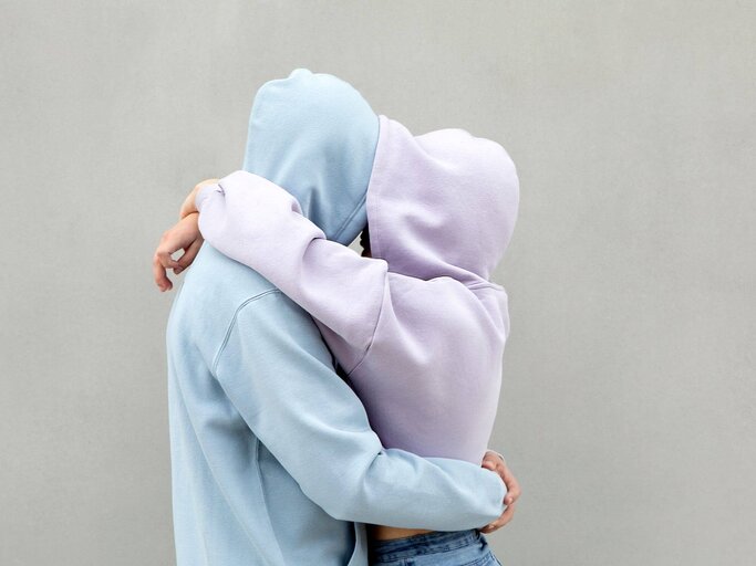 Paar mit Hoodie an umarmt sich  | © Getty Images/Westend61