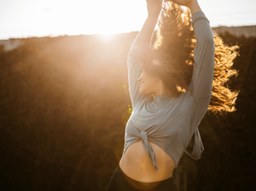 Frau tanzt in der Sonne | © Getty Images/The Good Brigade
