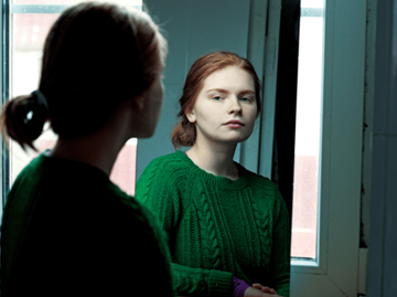Rothaarige Frau betrachtet sich im Spiegel | © Getty Images/Stepan Obruchkov photography