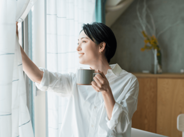 Frau mit Kaffeetasse am Fenster | © Getty Images/Five