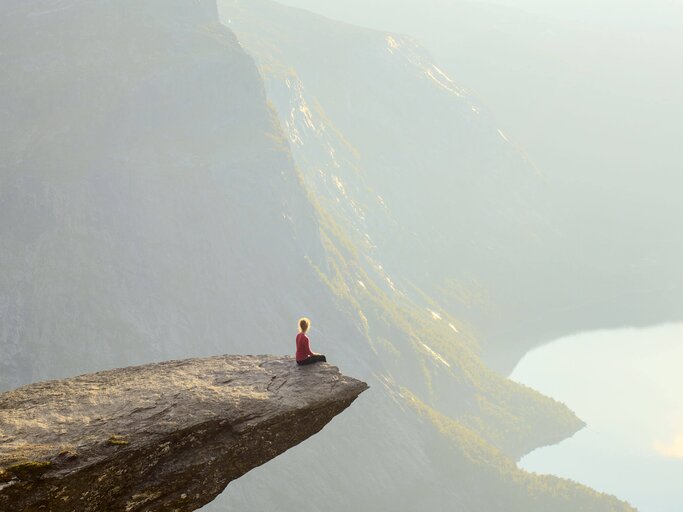 Frau sitzt am Rand eines Steins, der meterhoch | © Getty Images/Tatiana Kolesnikova