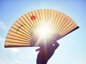 Frau hält Fächer gegen das Sonnenlicht | © Getty Images/Kirsty Renshaw / EyeEm