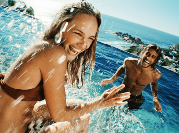 Frau und Mann spritzen sich im Pool nass | © Getty Images/Laurence Monneret