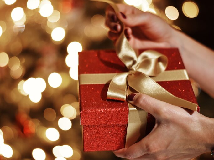 Frau packt Weihnachtsgeschenk aus | © Getty Images/Victoria Ambrosi