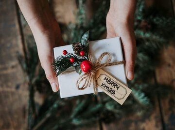 Hände mit Weihnachtsgeschenk | © Getty Images/Svante Berg
