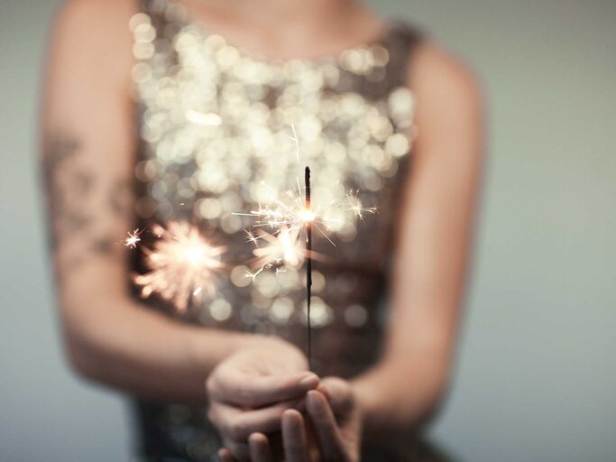 Frau mit Glitzerkleid und Wunderkerze | © Adobe Stock/Kanea