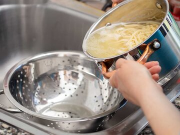 Frau schüttet Nudelwasser aus dem Topf in das Waschbecken. | © Getty Images / INAOX