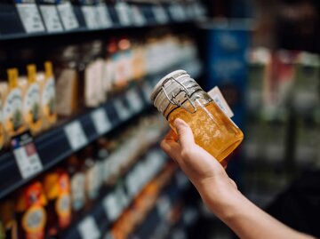 Honigglas in der Hand einer Käuferin | © Getty Images/d3sign