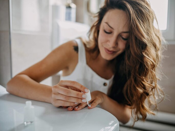 Frau lackiert sich die Fingernägel | © Getty Images/supersizer