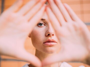 Frau formt Dreieck mit den Händen vor ihrem Gesicht | © Getty Images/Sarah Köster / EyeEm
