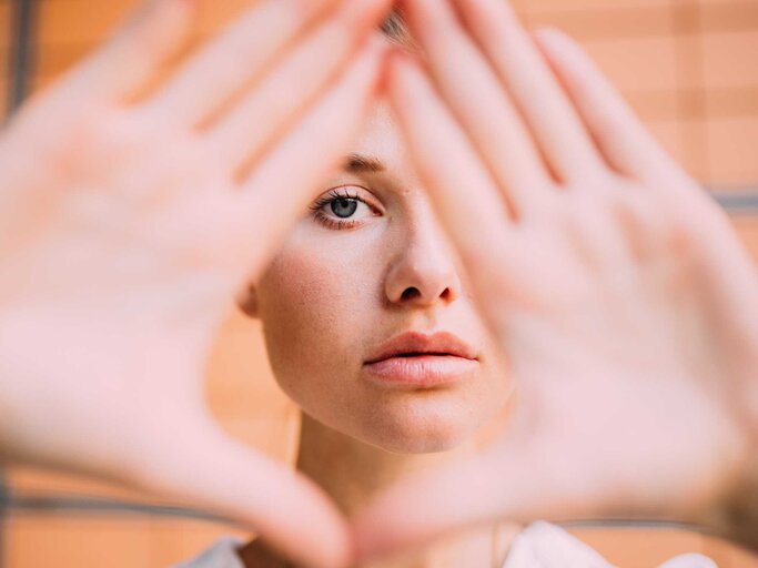 Frau formt Dreieck mit den Händen vor ihrem Gesicht | © Getty Images/Sarah Köster / EyeEm