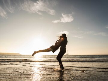 Pärchen am Strand fällt sich in die Arme | © Getty Images/Westend61