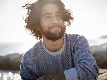 Mann mit langen Haaren in der Sonne am Strand | © Getty Images/The Good Brigade