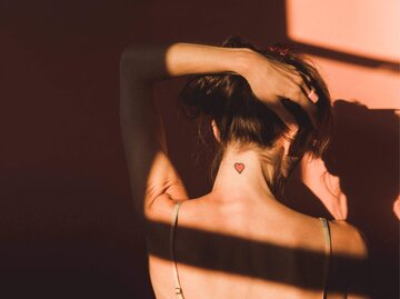 Frau mit Herztattoo im Nacken | © Getty Images/Jena Ardell