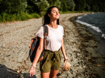 Junge Frau steht am Strand mit geschlossenen Augen | © Getty Images/MStudioImages