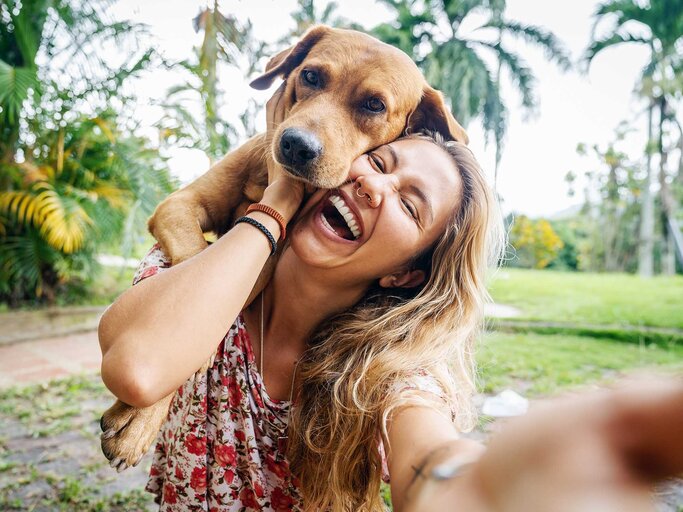 Junge Frau macht ein Selfie mit ihrem hellbraunen Labrador. | © Getty Images / Circle Creative Studio