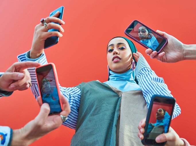 Frau mit Kopftuch wird von allen Seiten mit dem Handy fotografiert | © Getty Images/We Are